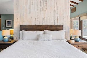 A bed with a wooden headboard, two bedside tables with lamps, and a framed picture on the wall. - H1872: Luxurious Villa, Stunning Ocean Views, 6 Seater Cart, BBQ (Avalon)