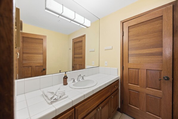 A bathroom with a wooden door, a sink, a mirror, and a towel rack. - H1872: Luxurious Villa, Stunning Ocean Views, 6 Seater Cart, BBQ (Avalon)