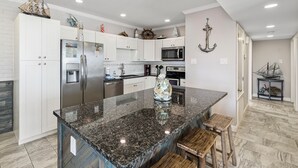 A modern kitchen with white cabinets, stainless steel appliances, and a granite island. - Beautiful condo located on the ship channel and in the heart of Port Aransas! Th (Port Aransas)