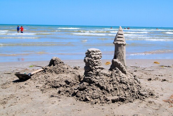 A sandy beach with a large sandcastle and a conical structure. - Beautiful condo located on the ship channel and in the heart of Port Aransas! Th (Port Aransas)