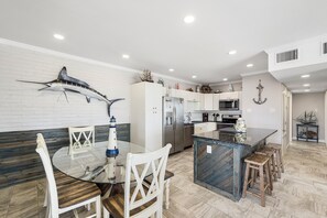 A modern kitchen with a central island, white cabinetry, and nautical-themed decor.