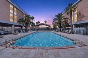 Relax by the spacious outdoor pool as the evening sky sets the scene, surrounded by swaying palms and comfortable poolside seating.