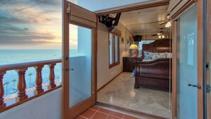 A balcony with a view of the sea, a bedroom with a bed and dresser, and a hallway with a lamp. - H249: Gorgeous Villa,NO STEPS,Panoramic Ocean Views,Private Balcony, 6-Seat Cart (Avalon)