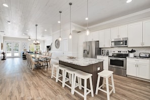 Enjoy cooking in this well-equipped kitchen with a central island, stainless steel appliances, and white cabinetry.