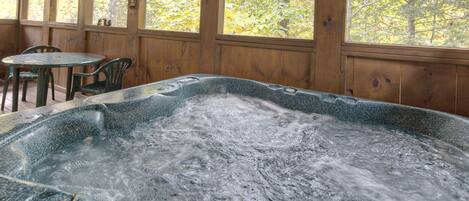 Un bain à remous dans un chalet en bois, avec vue sur les arbres aux couleurs automnales.