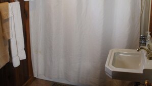 Een badkamer met douchegordijn, wastafel en handdoekhouder.