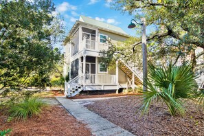 A two-story house with a balcony, a staircase, and a well-maintained garden. - Purple Parrot 2nd Floor Condo w Loft (Pensacola)