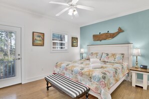 Una camera da letto con un letto, una panca, una ventola a soffitto e un'ornamento a forma di pesce appeso al muro.