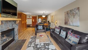 A living room with a fireplace, a leather sofa, a coffee table, and a TV mounted on the wall.