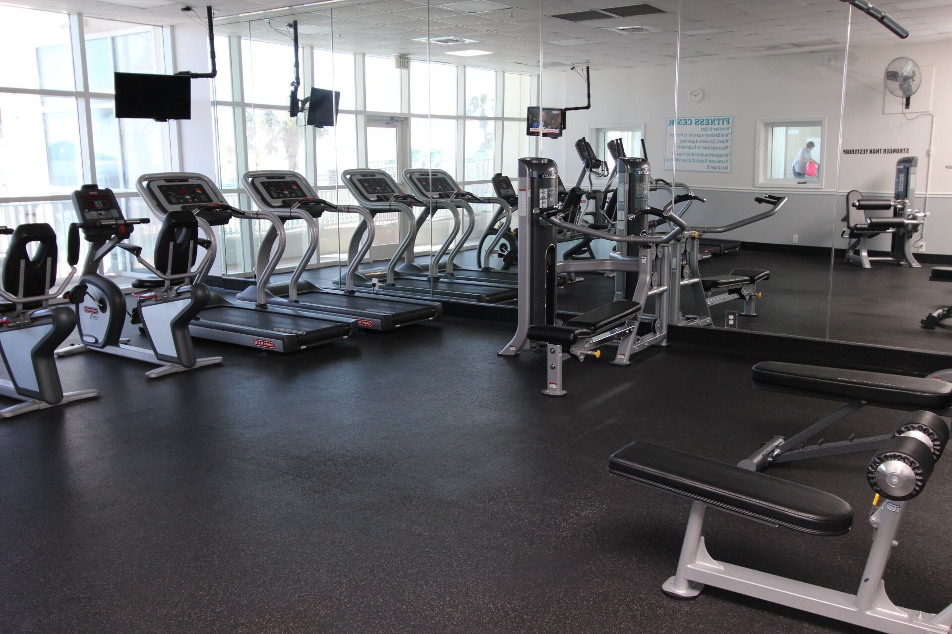 Ett gym med löpband, styrketräningsmaskiner och en träningsbänk.
