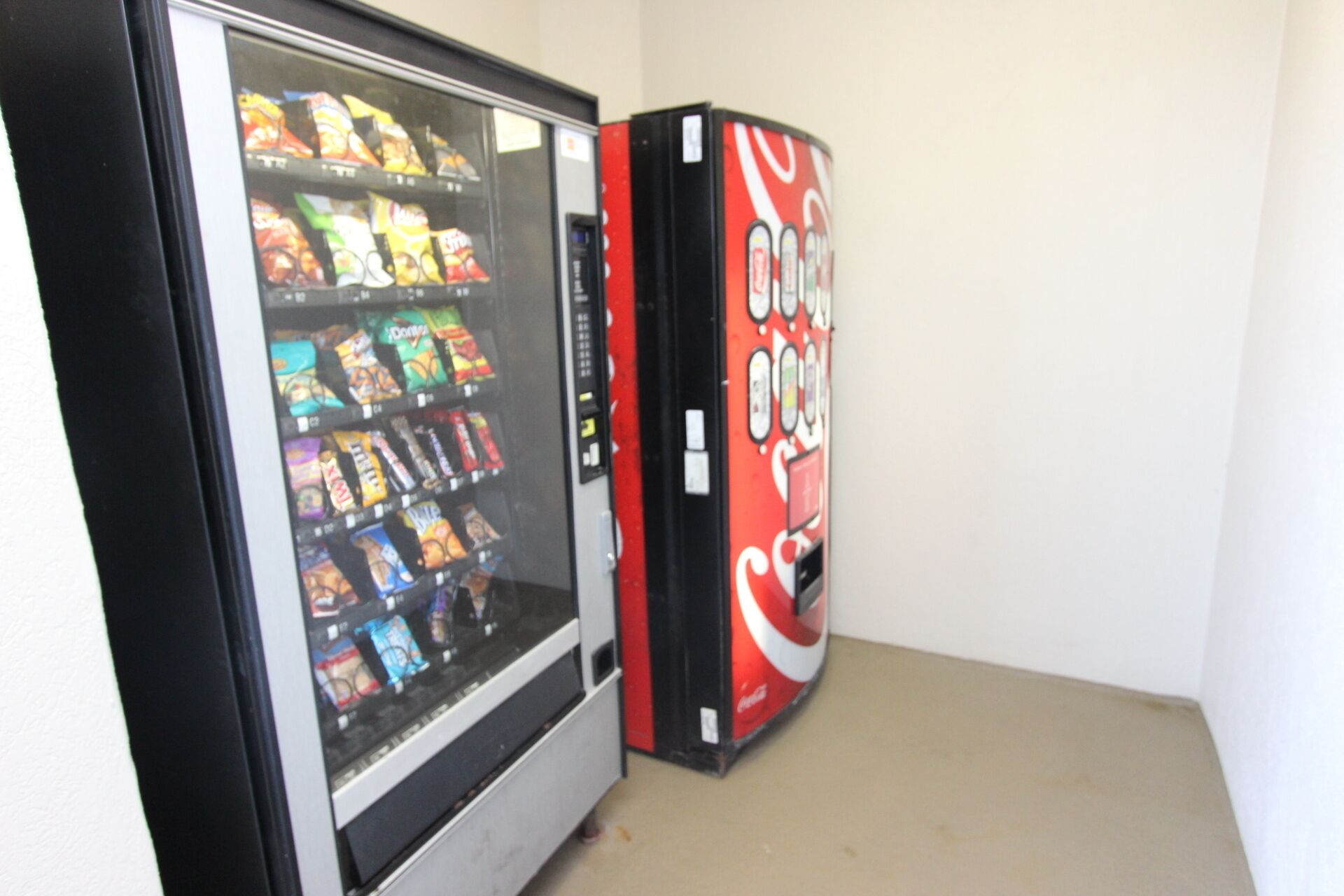 Un distributeur automatique de collations et un autre distributeur arborant la marque Coca-Cola.