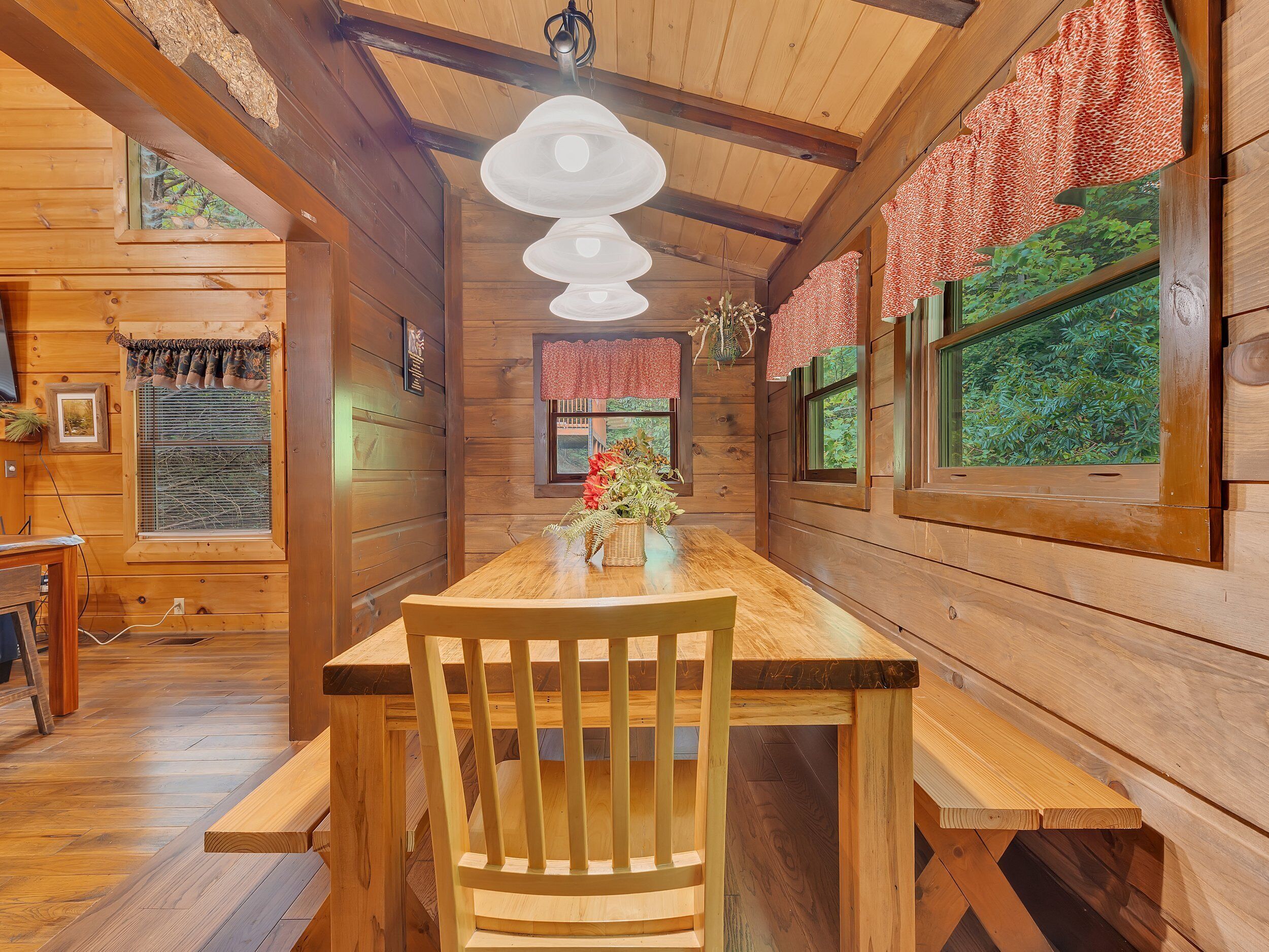 Ein Interieur einer Holzhütte mit Esstisch, Stühlen und einer Hängeleuchte.