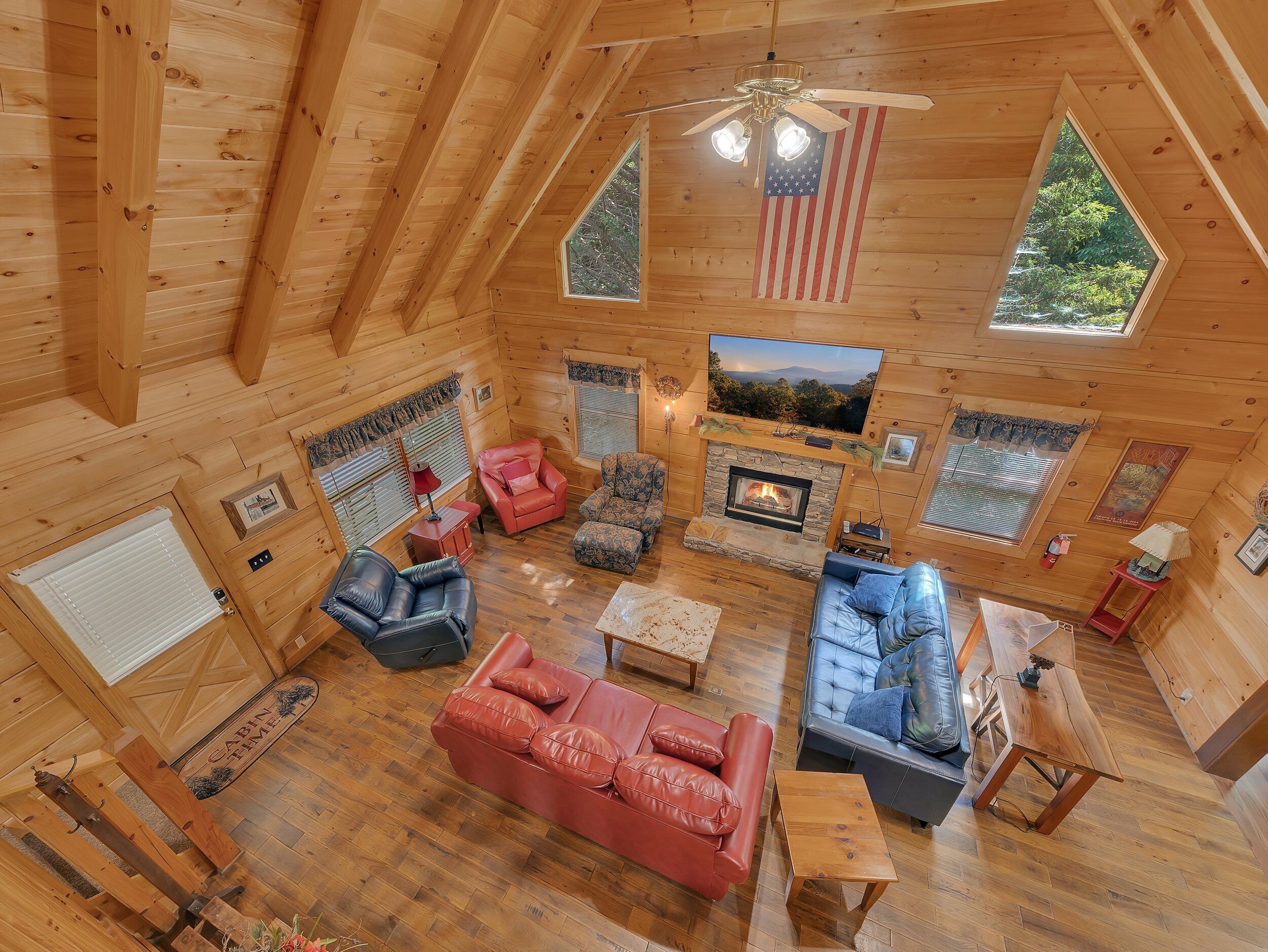 L'intérieur d'une cabane avec une cheminée, des murs en bois et un ventilateur de plafond.