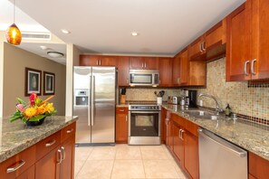 A modern kitchen with wooden cabinets, stainless steel appliances, and a tiled backsplash. - Honua Kai | Ocean View Studio | Car Incl. w/ 6+ Nights | HKH-423 by KBM (Lahaina)