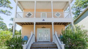 A two-story house with a balcony, a front door, and a sign above the door. - Oceanfront Opulence: Vacation Home with Amazing Pool, Beach Just Moments Away (Pensacola)