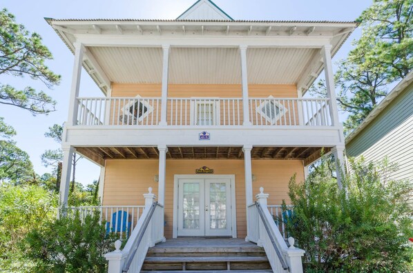 A two-story house with a balcony, a front door, and a sign above the door.
