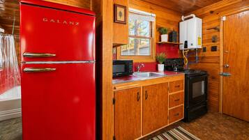 Una cocina compacta con armarios de madera, un refrigerador Galanz rojo, un microondas y una estufa.