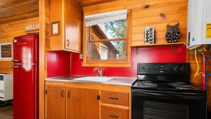 Una cucina compatta con un frigorifero rosso, un fornello e pensili in legno.