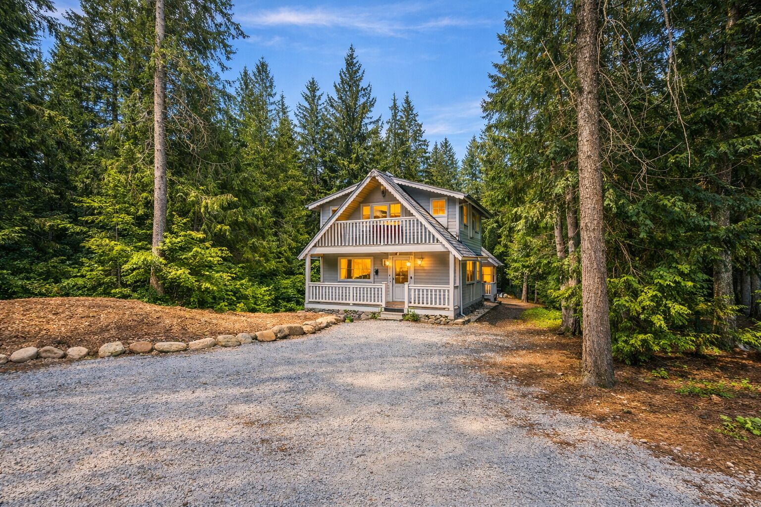 A two-story cabin with a porch, surrounded by dense forest.