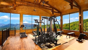 Une salle de sport équipée de matériel d’exercice et dotée de grandes fenêtres offrant une vue sur les montagnes.