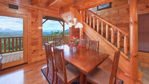 Une cabane en bois comprenant un coin repas, un escalier et une vue sur les montagnes.