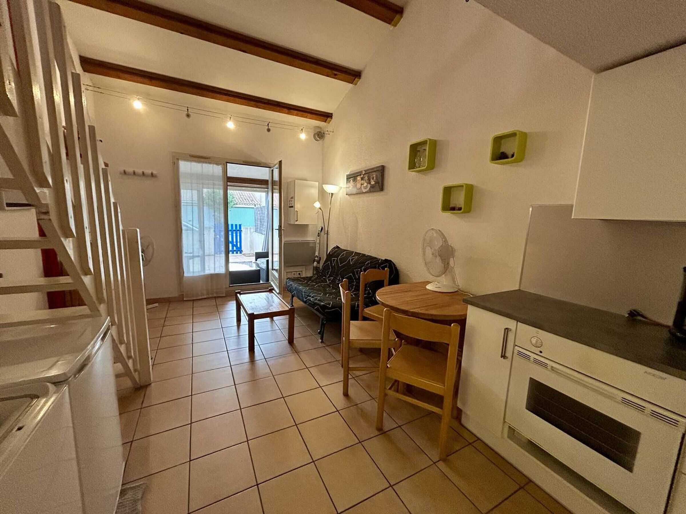 A compact kitchen with a dining area, a built-in oven, and a staircase leading to another room.