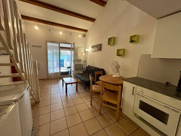 A compact kitchen with a dining area, a built-in oven, and a staircase leading to another room.