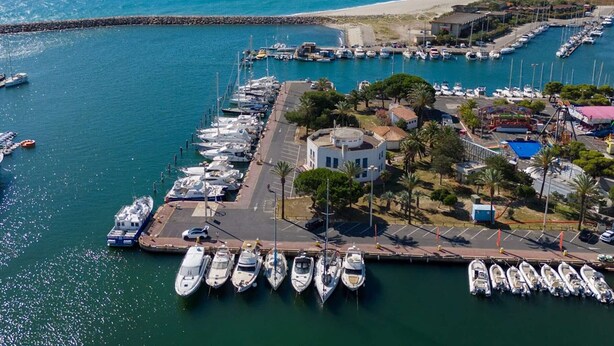 A marina with boats docked, a beach in the background, and a small building with a red roof. - Cozy 2-Room House with Mezzanine, Pool & Parking - Saint-Cyprien Beach (Saint-Cyprien)