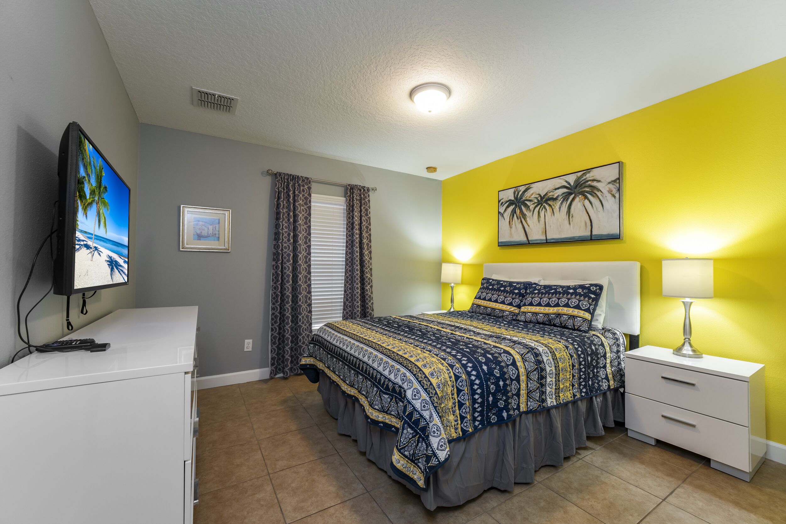A bedroom with a bed, bedside tables, a TV, and a painting on the wall.