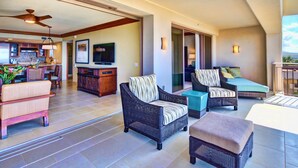 Amplia sala de estar con muebles de mimbre, una cocina al fondo y un balcón con vistas.