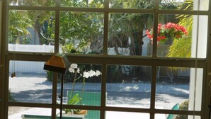 A room with a large window overlooking a garden and a pool area. - Castaway Cottage + Beach + Heated Private Pool & Spa + GOLF CART INCLUDED! (Anna Maria)