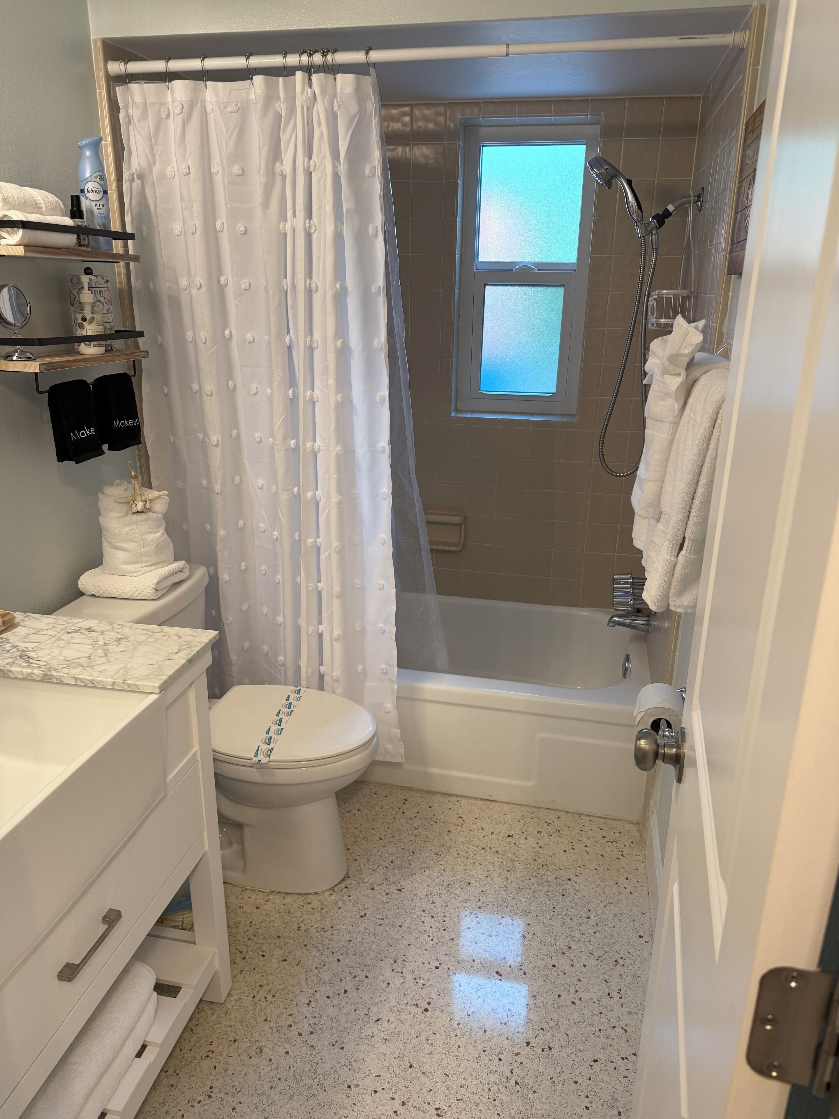 Une salle de bain comprenant des toilettes, un lavabo, un meuble-lavabo, une douche et une fenêtre.