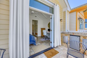 Porta de correr de vidro aberta que dá para um quarto com uma cama, uma escrivaninha e uma cadeira.
