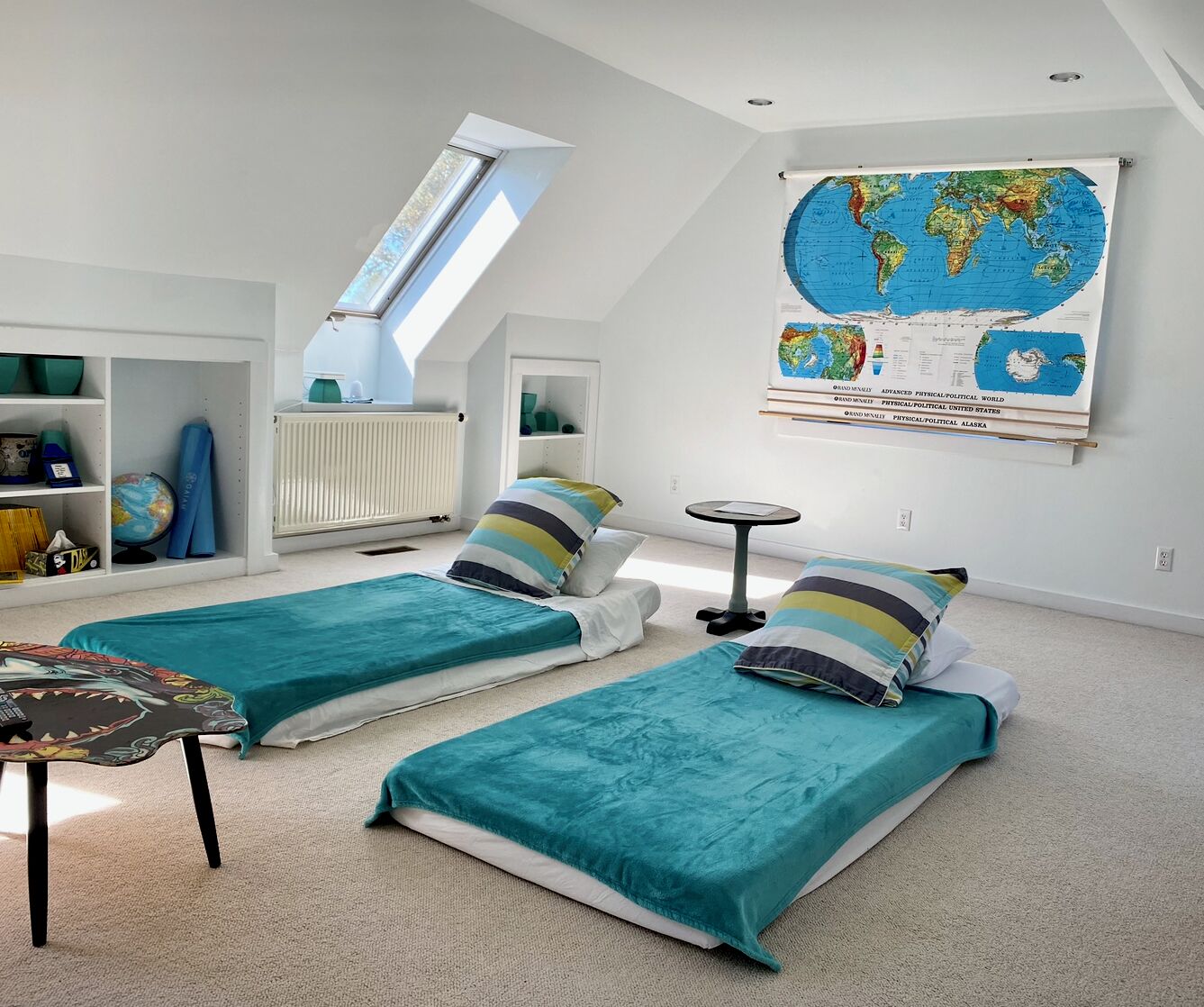 Quarto com duas camas, um mapa-múndi na parede, um claraboia e uma estante com livros e um globo.