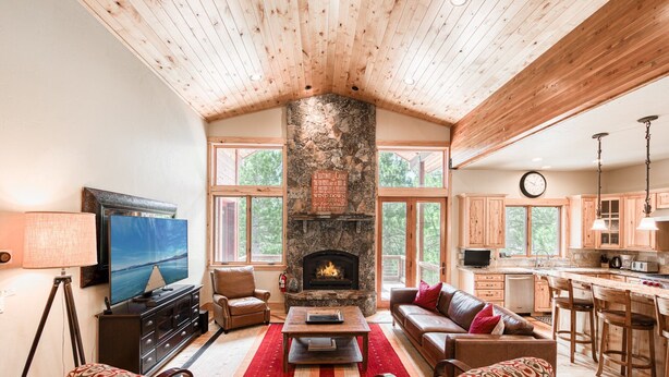 A spacious living room with a stone fireplace, a television, and comfortable seating.