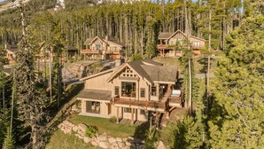 Una cabaña con varias cabañas rodeada de bosque y montañas.