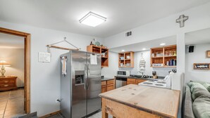 Una cocina moderna con un refrigerador de acero inoxidable, armarios de madera y una mesa de madera.