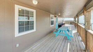 Una terraza techada con una mesa de picnic, ventanas amplias y vistas al paisaje.