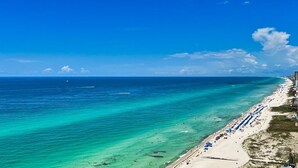 A beach with clear turquoise waters, a long sandy shore, and a pier extending into the sea. - 4 Bedroom Platinum Designer End Unit Incredible Gulf Views! Free Beach Chairs (Panama City Beach)