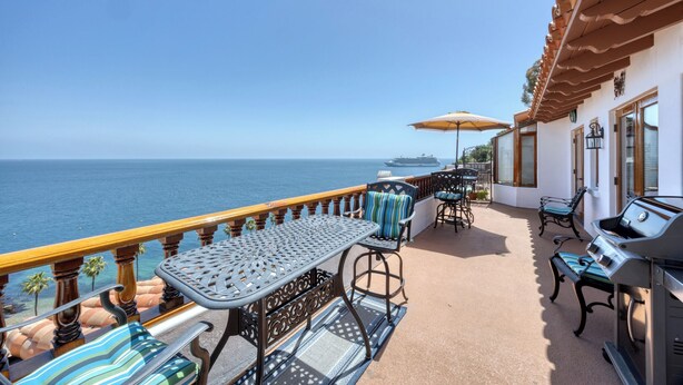 Un balcón con mobiliario exterior, una parrilla y vistas al océano.