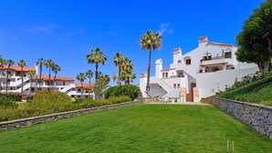 Un edificio grande y blanco con varios balcones y una pared de piedra.