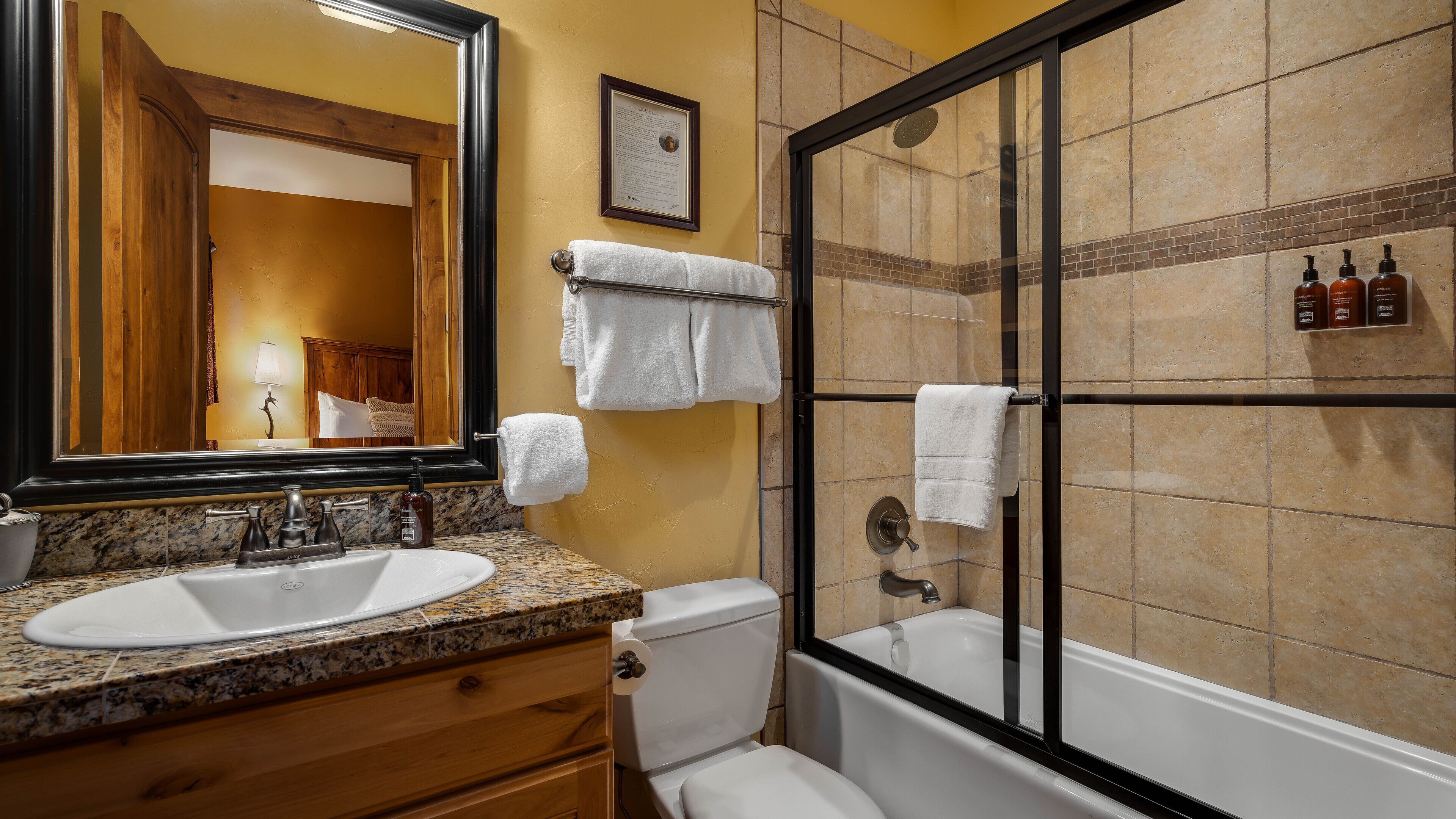 Une salle de bain équipée d’un lavabo, de toilettes et d’une douche à parois de verre.