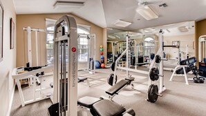 Ein Fitnessstudio mit unterschiedlichen Trainingsgeräten, darunter eine Hantelbank, ein Squat-Gestell und Kurzhanteln.