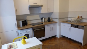 A compact kitchen with white cabinets, a microwave, a stove, a dishwasher, and a sink.
