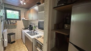 A compact kitchen with wooden cabinets, a built-in oven, a sink, and a window providing natural light. - Spacious 4-Room Apartment for 9 - Ski Lift, Balcony, Garage - Alpe d'Huez (Huez)