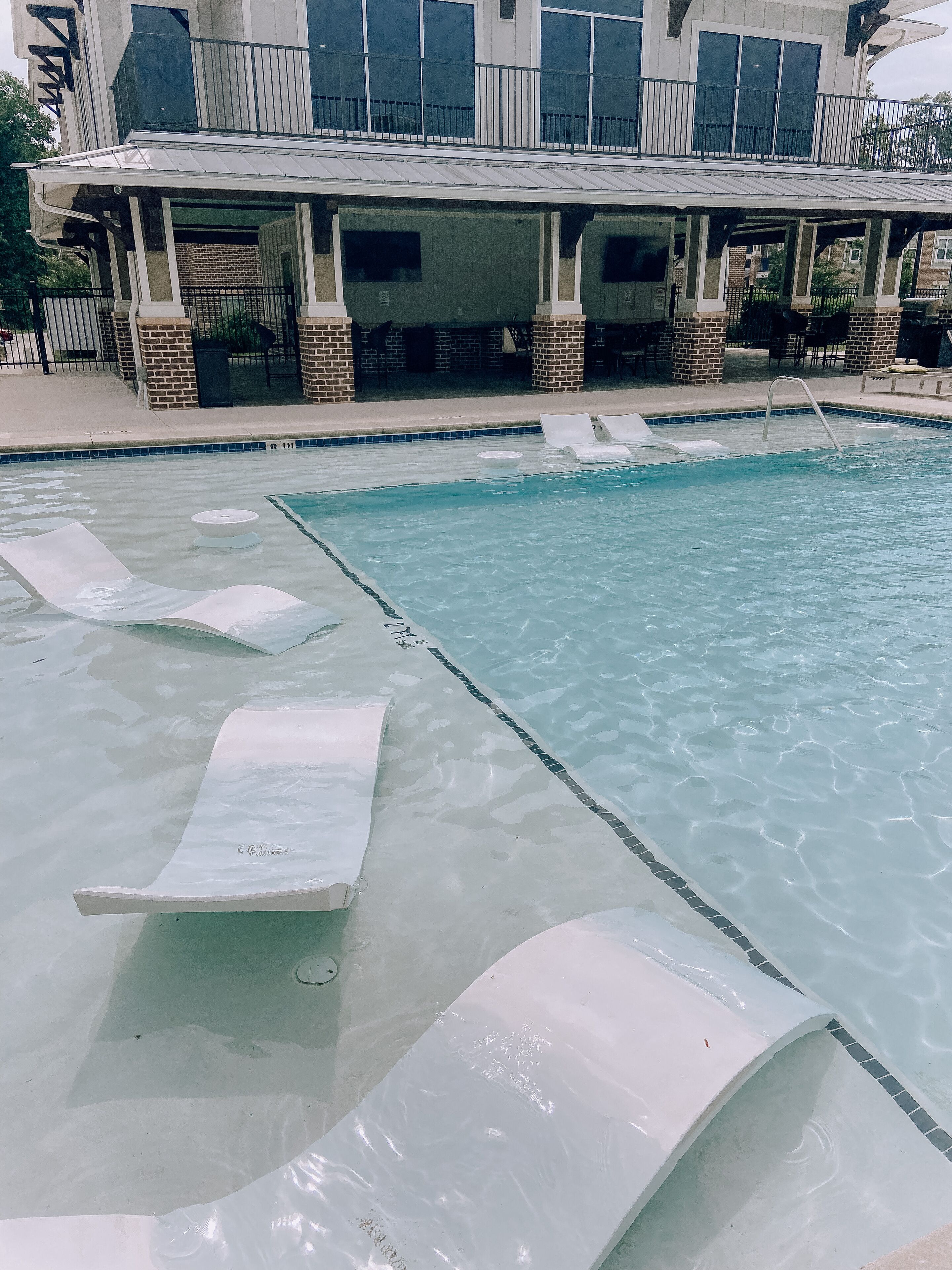 Une piscine dotée de chaises longues et d’un espace de détente abrité.