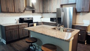 A modern kitchen with granite countertops, stainless steel appliances, and wooden cabinets.