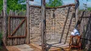 Eine rustikale Steinmauer mit einem Holztor und einem kleinen Hocker mit weißem Bezug.