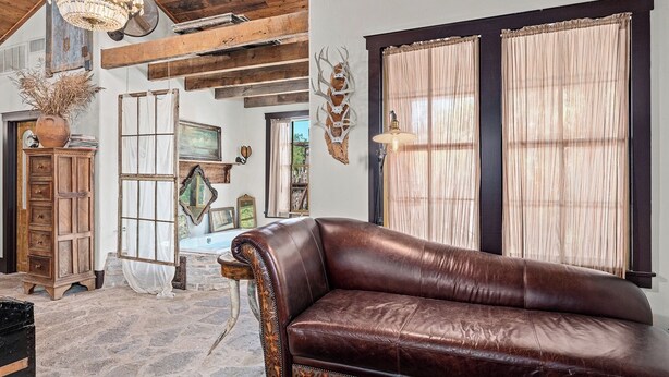 Ein rustikales Interieur mit Ledersofa, Holzbalken und einer Chandelier.