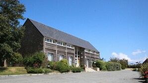A large, modern building with a flat roof and multiple windows. - Cozy house in La Hague (La Hague)